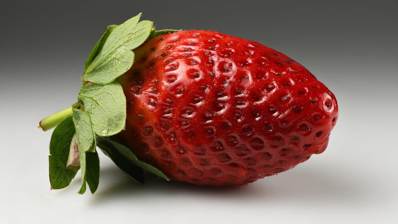 Fresh whole strawberry with seeds and green calyx, botanical comparison to sea buckthorn vitamin C content